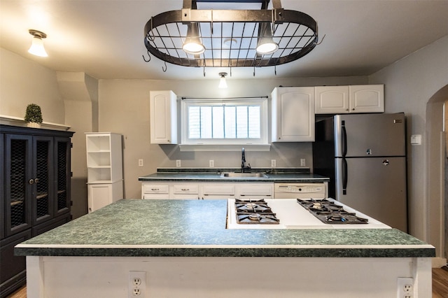 kitchen featuring white appliances, arched walkways, a sink, white cabinetry, and dark countertops