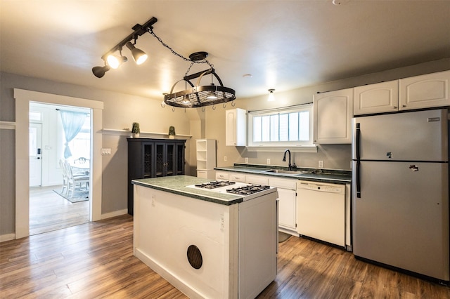 kitchen featuring dark countertops, white appliances, wood finished floors, and a sink