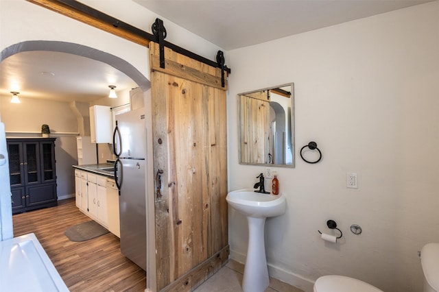 bathroom featuring toilet, wood finished floors, baseboards, and a sink