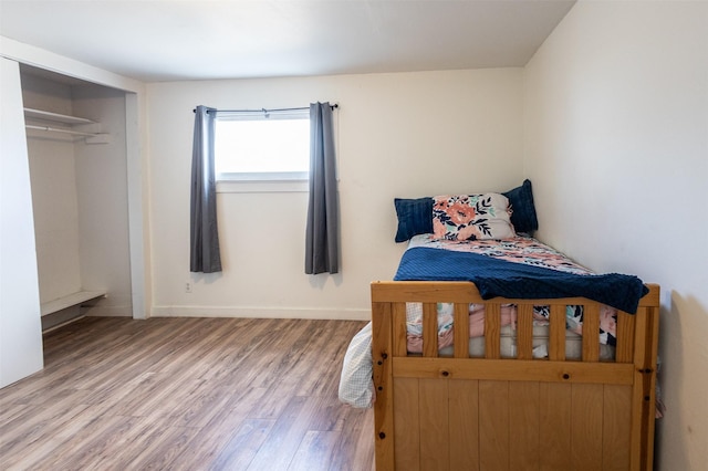 bedroom featuring a closet, baseboards, and wood finished floors