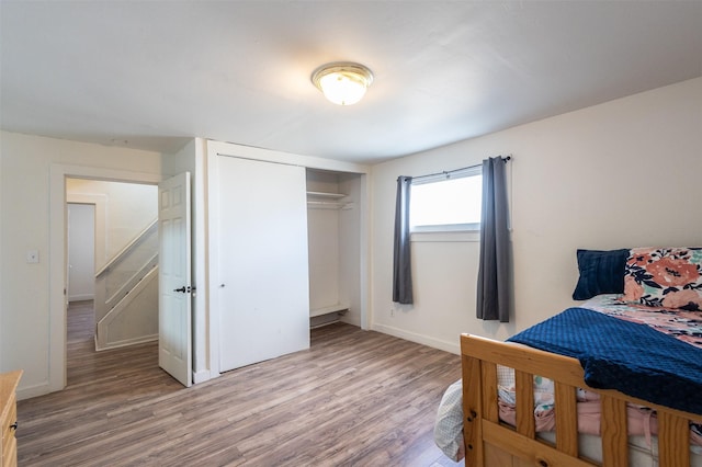 bedroom with a closet, light wood-type flooring, and baseboards