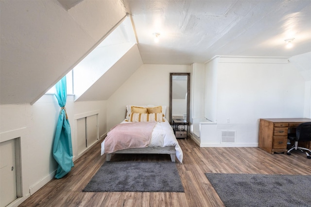 bedroom featuring vaulted ceiling, visible vents, baseboards, and wood finished floors