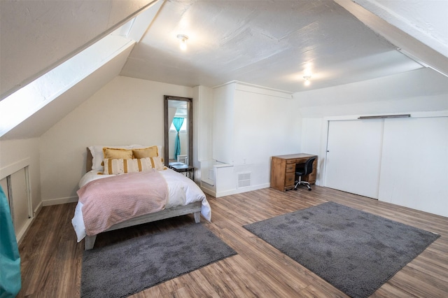 bedroom featuring visible vents, lofted ceiling, baseboards, and wood finished floors