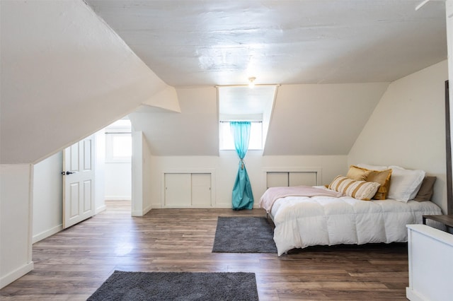 bedroom featuring baseboards, multiple windows, wood finished floors, and vaulted ceiling