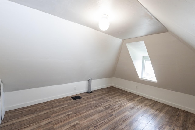 additional living space featuring visible vents, baseboards, dark wood finished floors, and vaulted ceiling