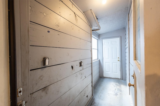 hallway with concrete flooring and wood walls