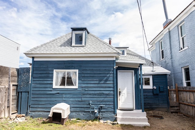 back of house with roof with shingles and fence