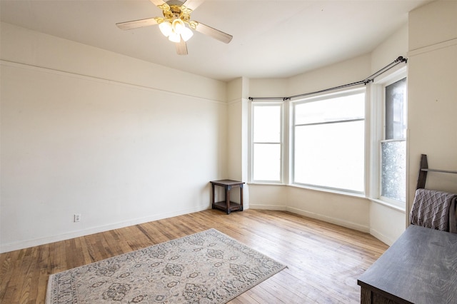 living area with ceiling fan, baseboards, and wood finished floors