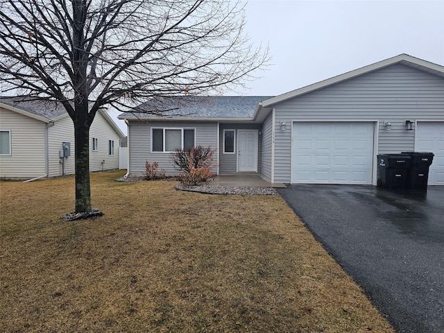 ranch-style house featuring aphalt driveway, an attached garage, and a front lawn