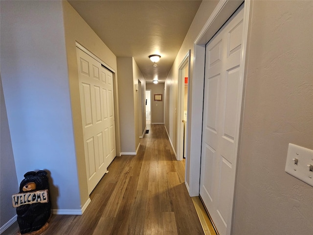 hallway with dark wood finished floors and baseboards