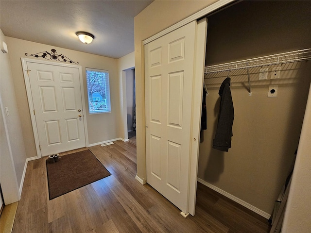 foyer entrance with wood finished floors and baseboards