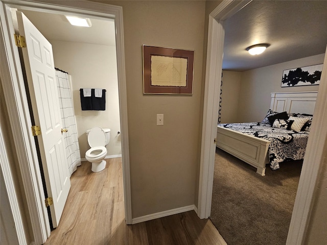 bathroom with baseboards, toilet, and wood finished floors