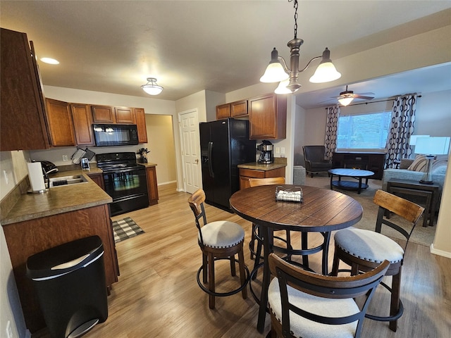 kitchen with brown cabinets, black appliances, light wood-type flooring, and a sink