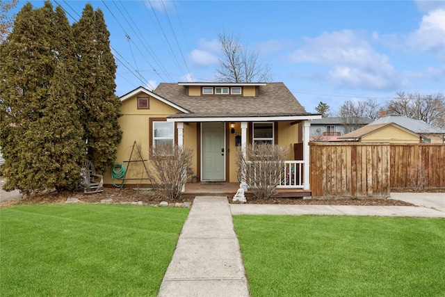 bungalow-style home with a front lawn, fence, roof with shingles, stucco siding, and covered porch