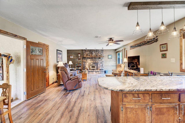 7415 Wildcat St, Helena, MT 59602 - kitchen with light wood-style floors, a fireplace, open floor plan, decorative light fixtures, and a ceiling fan