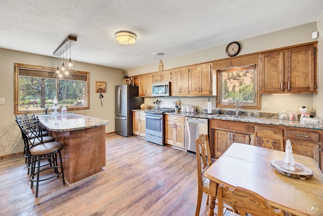 7415 Wildcat St, Helena, MT 59602 - kitchen featuring appliances with stainless steel finishes, a sink, light wood-type flooring, light stone counters, and a breakfast bar