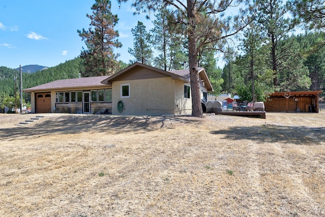 exterior space with a mountain view, a garage, and stucco siding