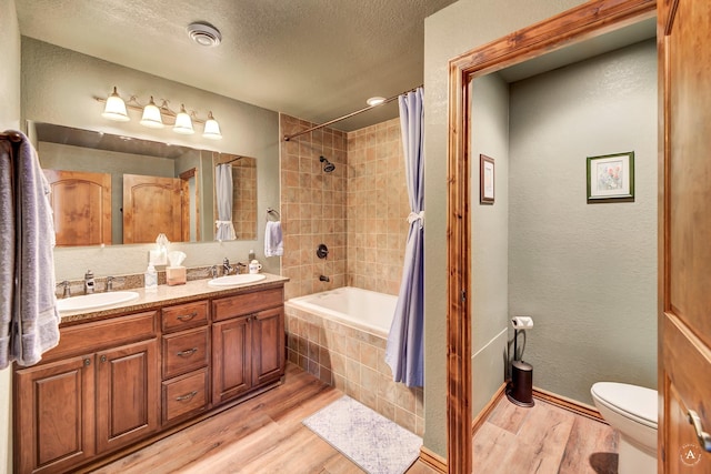 7415 Wildcat St, Helena, MT 59602 - bathroom with wood finished floors, toilet, double vanity, tiled shower / bath combo, and a textured ceiling