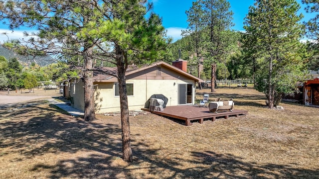 7415 Wildcat St, Helena, MT 59602 - view of side of property with a wooden deck, a chimney, and stucco siding