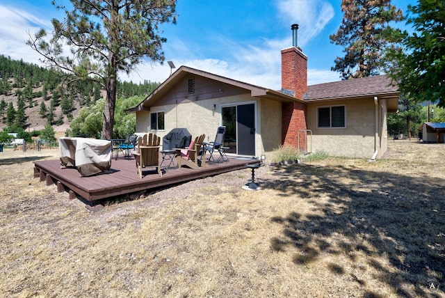 7415 Wildcat St, Helena, MT 59602 - back of property featuring stucco siding, a chimney, and a deck