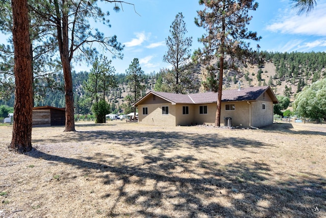 7415 Wildcat St, Helena, MT 59602 - view of side of property featuring stucco siding and a wooded view