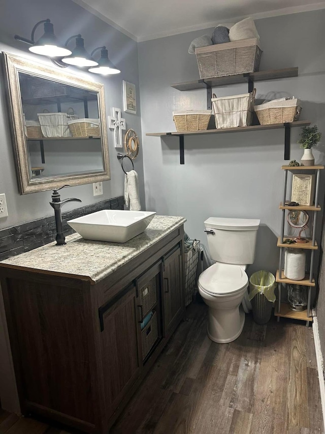 bathroom with toilet, wood finished floors, vanity, and crown molding