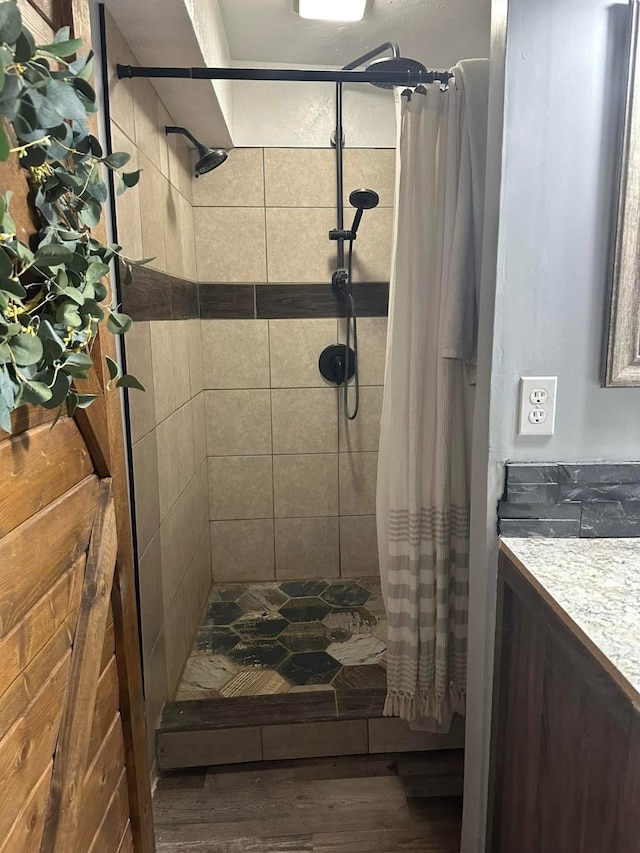 bathroom with a tile shower, vanity, and wood finished floors