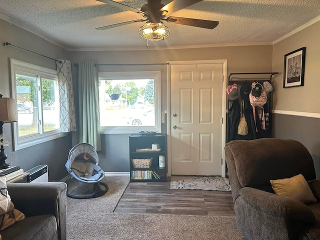 interior space with a ceiling fan, ornamental molding, wood finished floors, and a textured ceiling