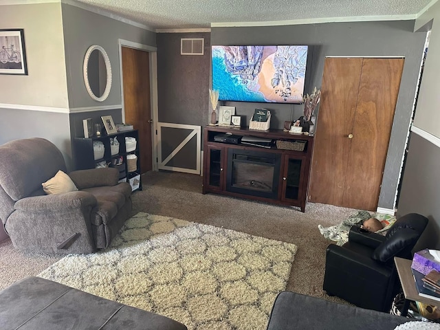 carpeted living room featuring a glass covered fireplace, crown molding, visible vents, and a textured ceiling