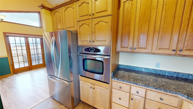 kitchen with light brown cabinetry, dark stone countertops, and stainless steel appliances