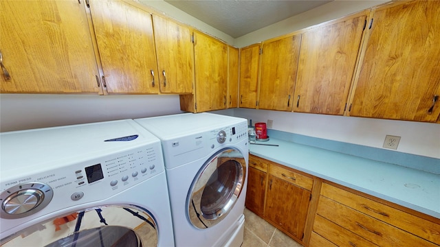 laundry room featuring cabinet space, a textured ceiling, light tile patterned flooring, and washer and clothes dryer