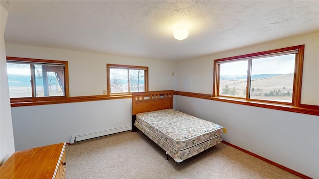 bedroom featuring carpet flooring, baseboards, baseboard heating, and a textured ceiling