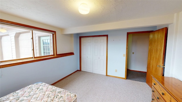 bedroom with a closet, carpet flooring, a textured ceiling, and baseboards