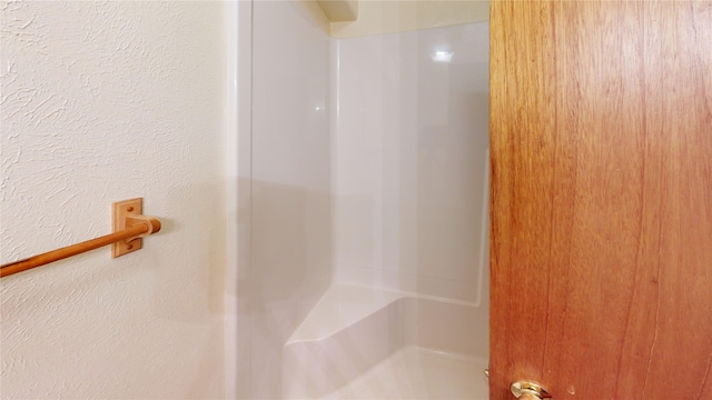 full bath featuring walk in shower and a textured wall