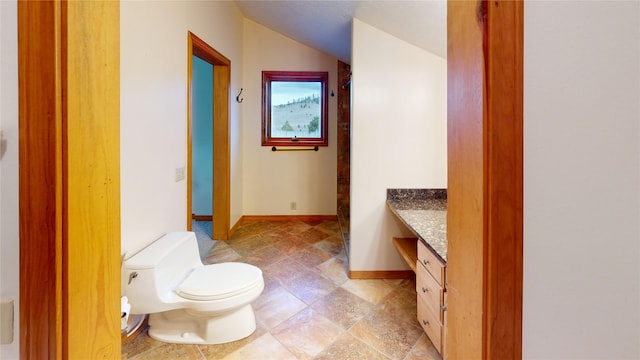 bathroom featuring toilet, vanity, lofted ceiling, and baseboards