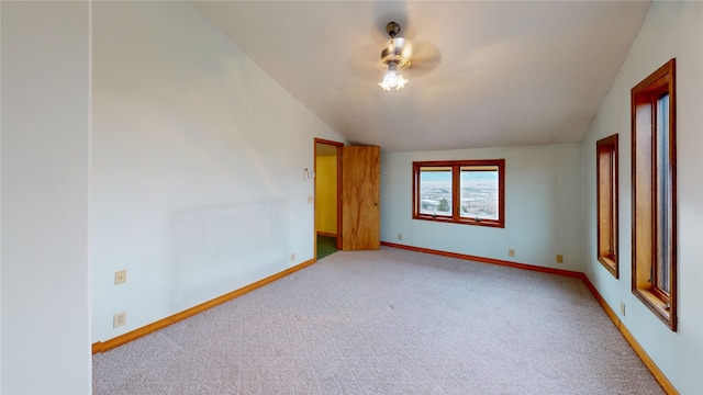 spare room featuring baseboards, lofted ceiling, light colored carpet, and ceiling fan