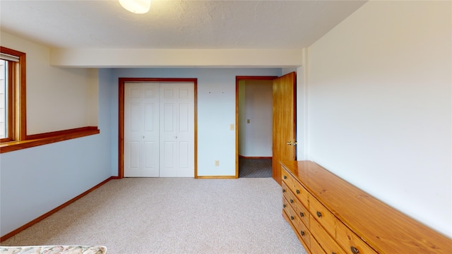 unfurnished bedroom featuring baseboards, carpet floors, and a closet