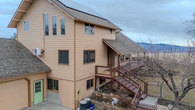 view of home's exterior with stairway, roof with shingles, and solar panels