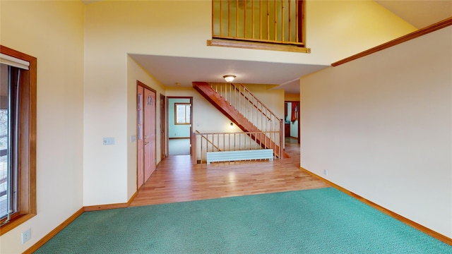 interior space with stairway, a high ceiling, baseboards, and wood finished floors