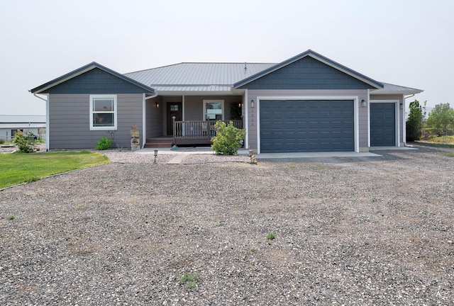 single story home featuring a porch, an attached garage, dirt driveway, and metal roof