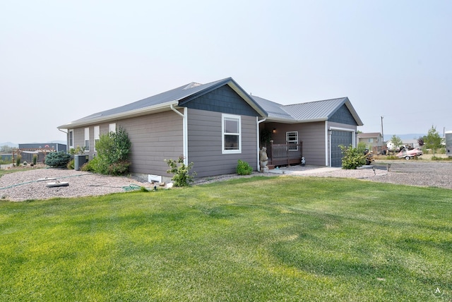 exterior space featuring a garage, metal roof, and a front yard