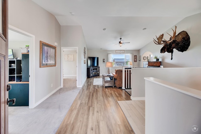 hallway featuring an upstairs landing, light wood-style flooring, and baseboards