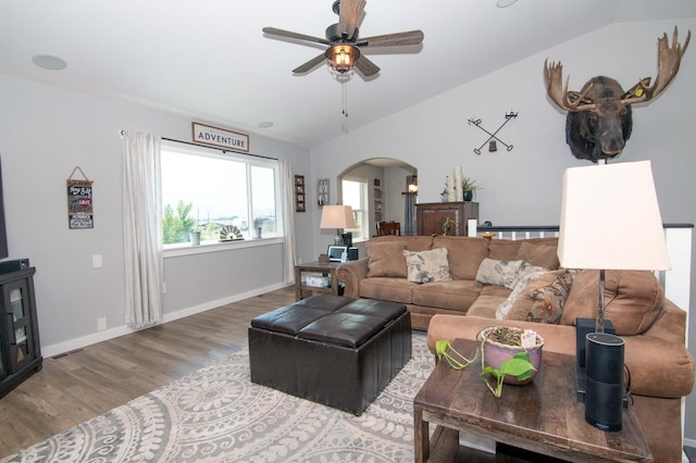 living area with arched walkways, lofted ceiling, wood finished floors, and a ceiling fan