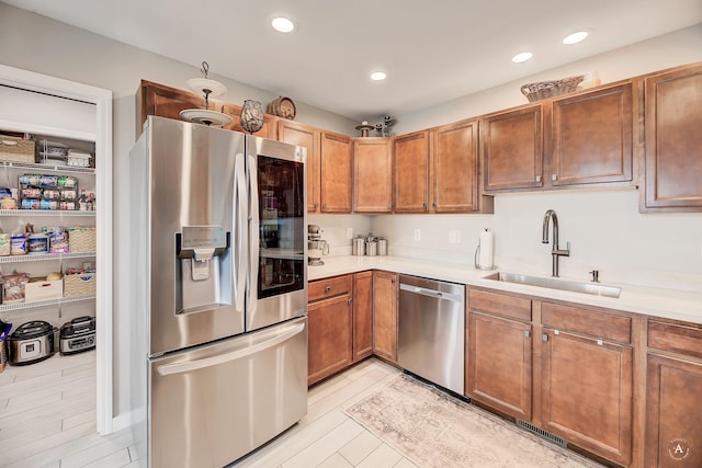 kitchen featuring a sink, stainless steel appliances, brown cabinetry, and light countertops