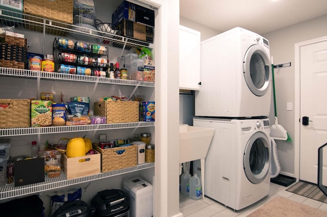 laundry area with tile patterned flooring, laundry area, and stacked washer and dryer