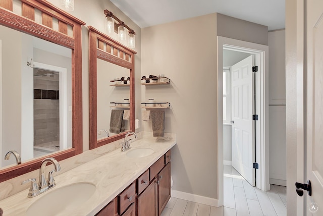 full bath with double vanity, baseboards, and a sink