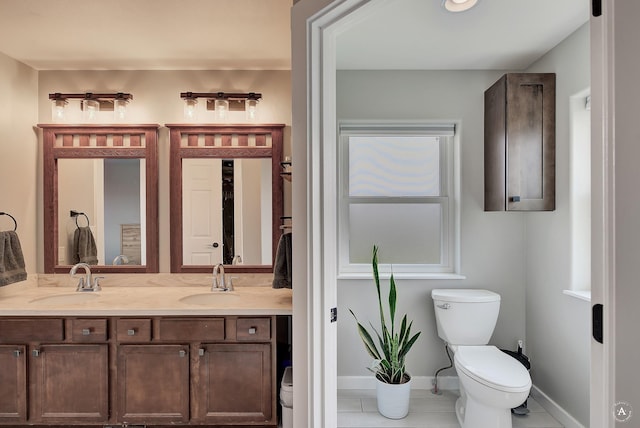 full bathroom featuring a sink, baseboards, toilet, and double vanity