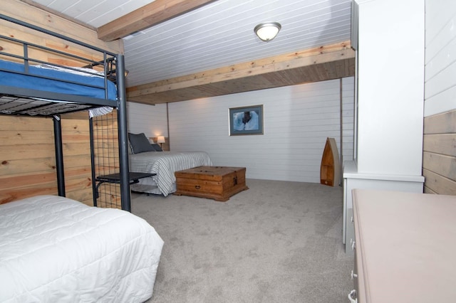 carpeted bedroom with beam ceiling and wood walls