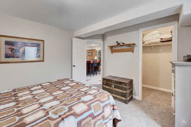 bedroom with light carpet, a spacious closet, baseboards, and a closet