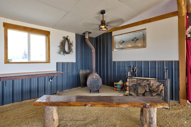 dining room featuring a wainscoted wall, a wood stove, and a ceiling fan